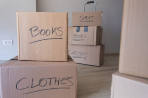 A stack of boxes with the words books and clothes written on them. The boxes are piled on top of each other, and the labels suggest that they are being packed for a move