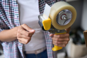 Close up photo of a person holding and using a packing tape holder.