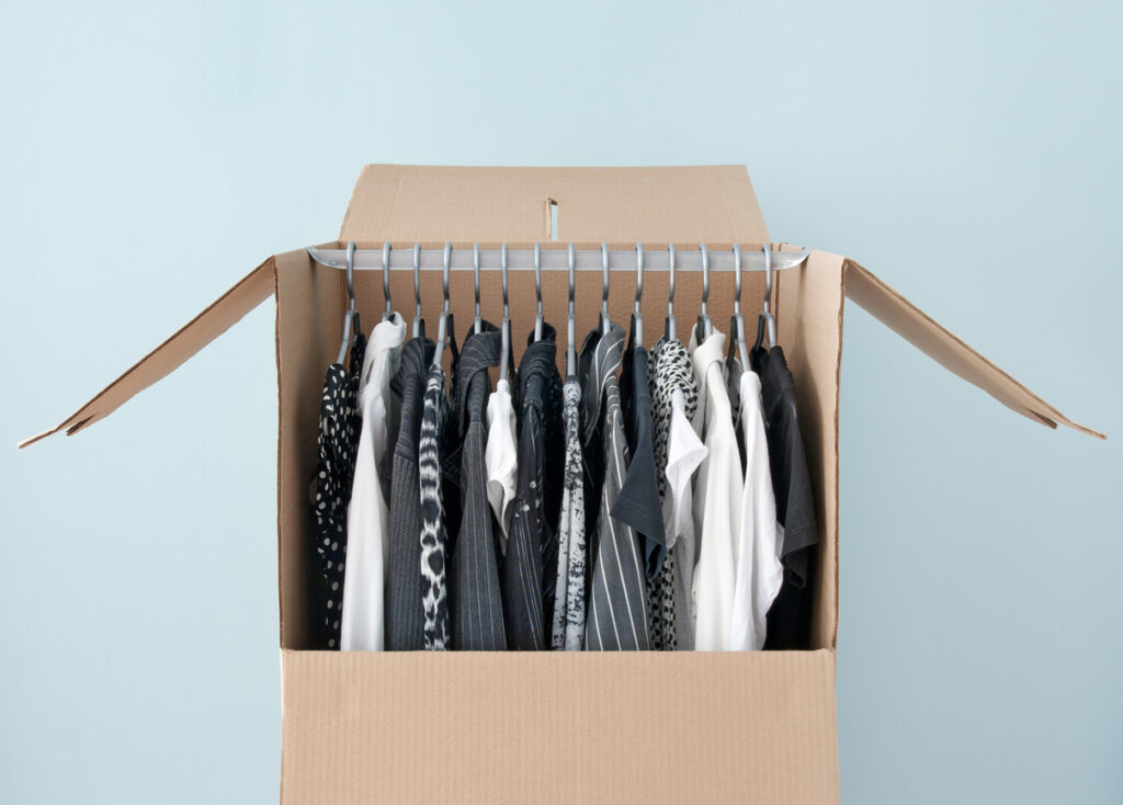 Black and white clothes hanging in a wardrobe box, prepared for moving.