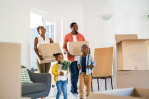 Family carrying boxes and moving into a new home together.